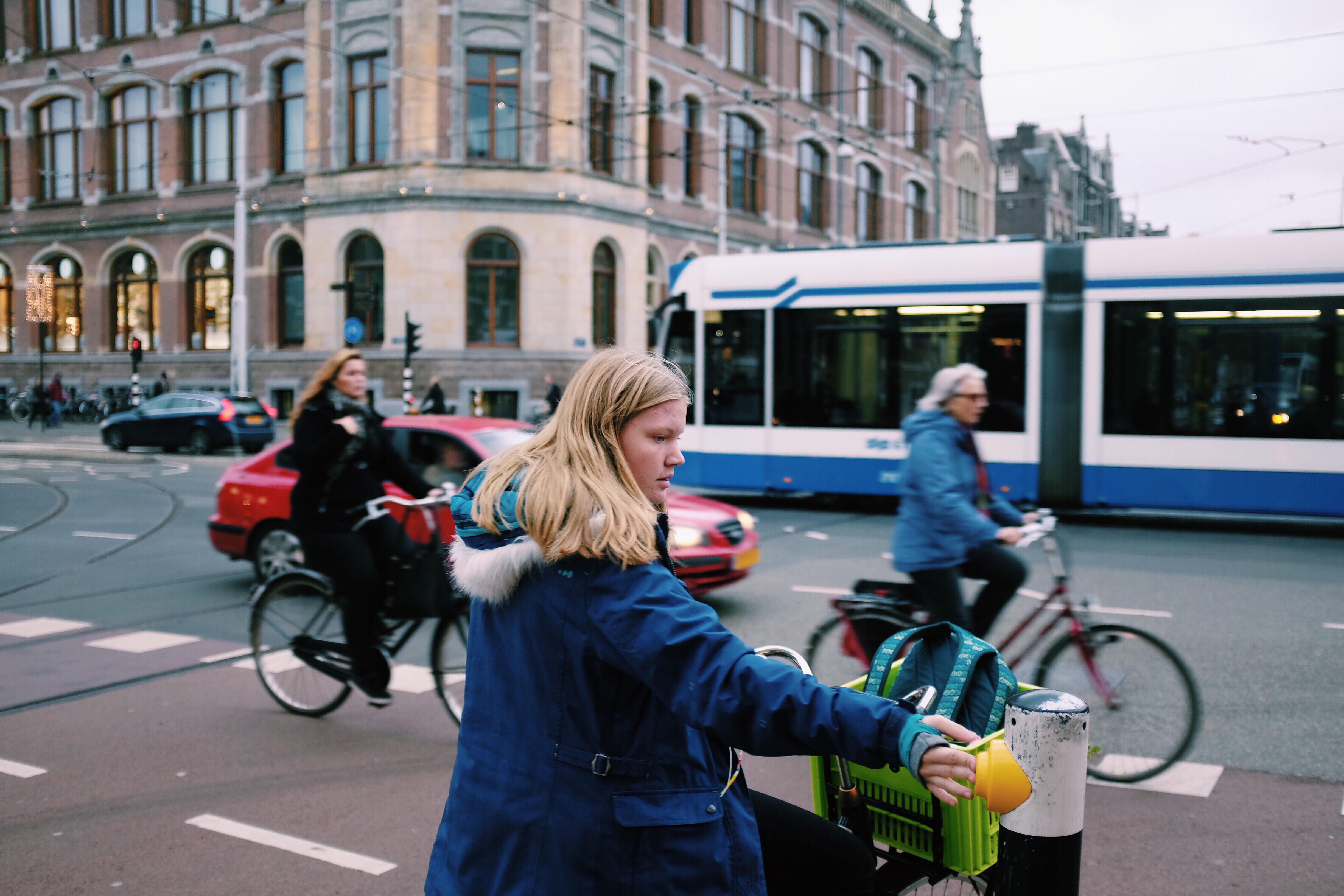 drie fietsers in de stad met een auto en tram op de achtergrond