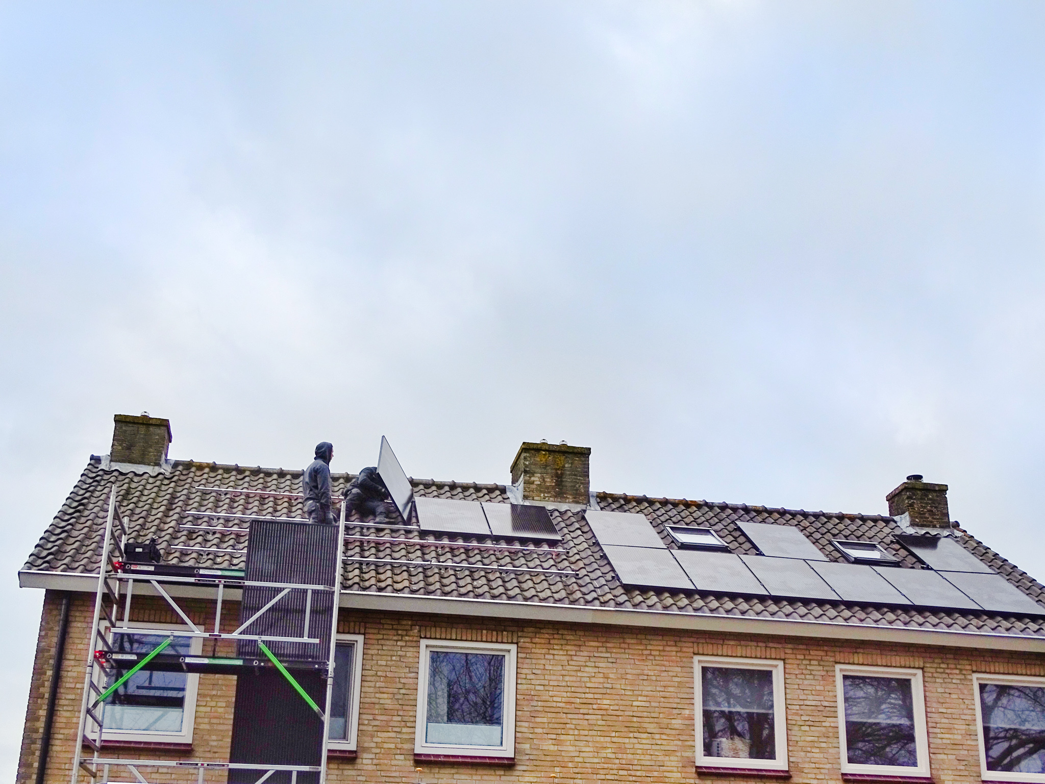 installateurs leggen zonnepanelen op het dak van een woning