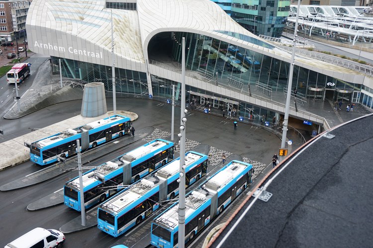 vier bussen wachten bij een bushalte naast het station