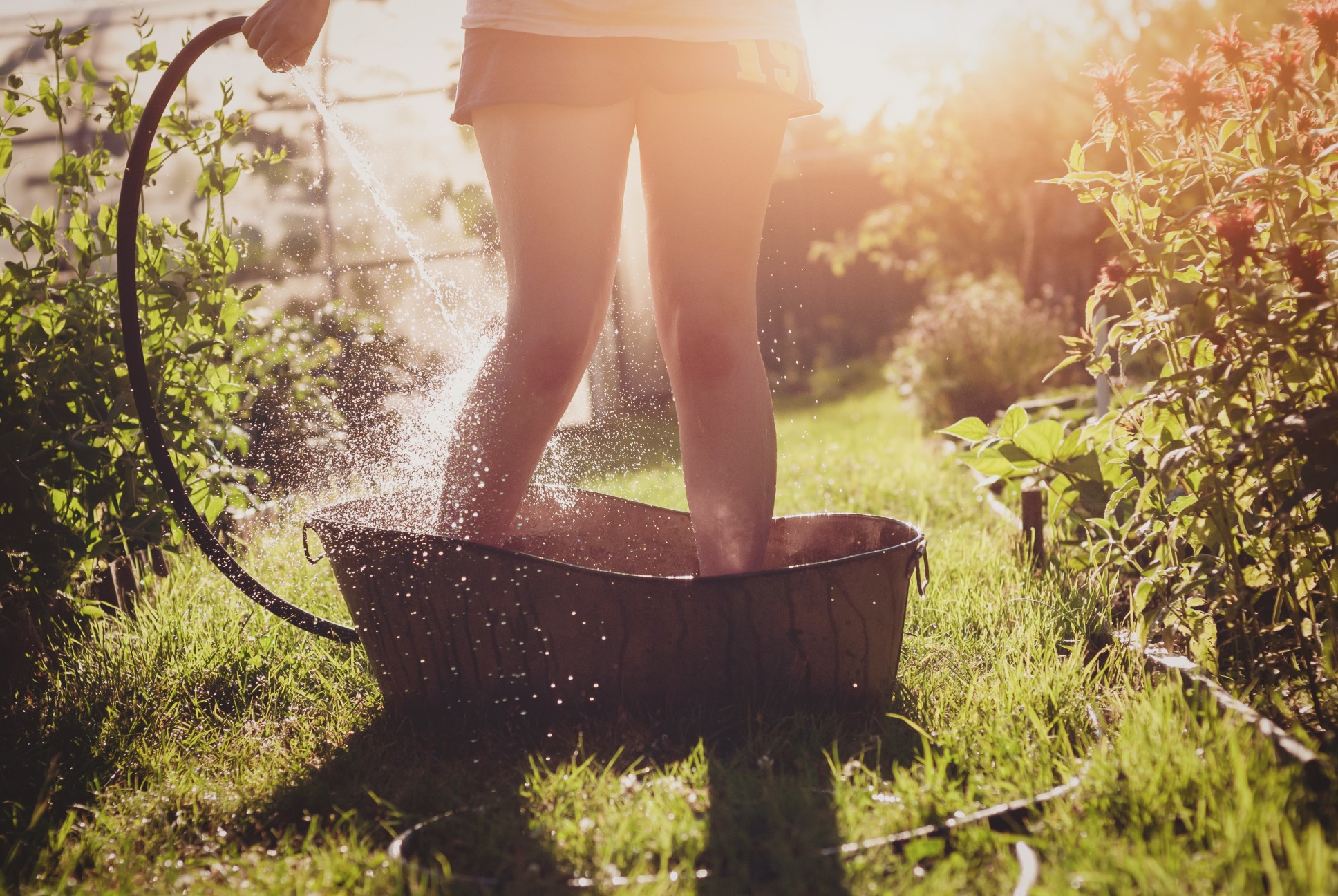 Een persoon staat in een teiltje die zij vult met water