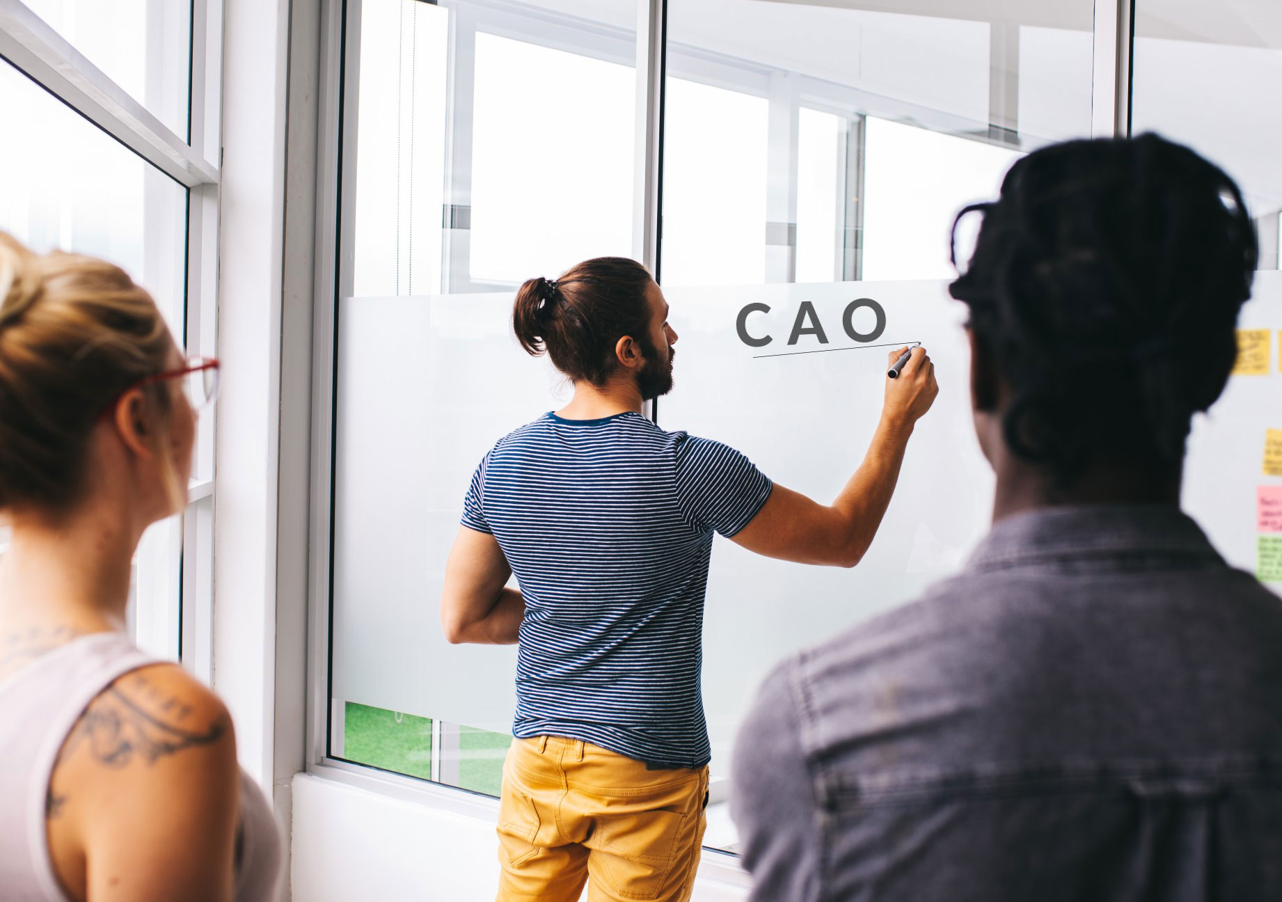 Een man schrijft de het woord CAO op een bord terwijl andere mensen naar hem kijken