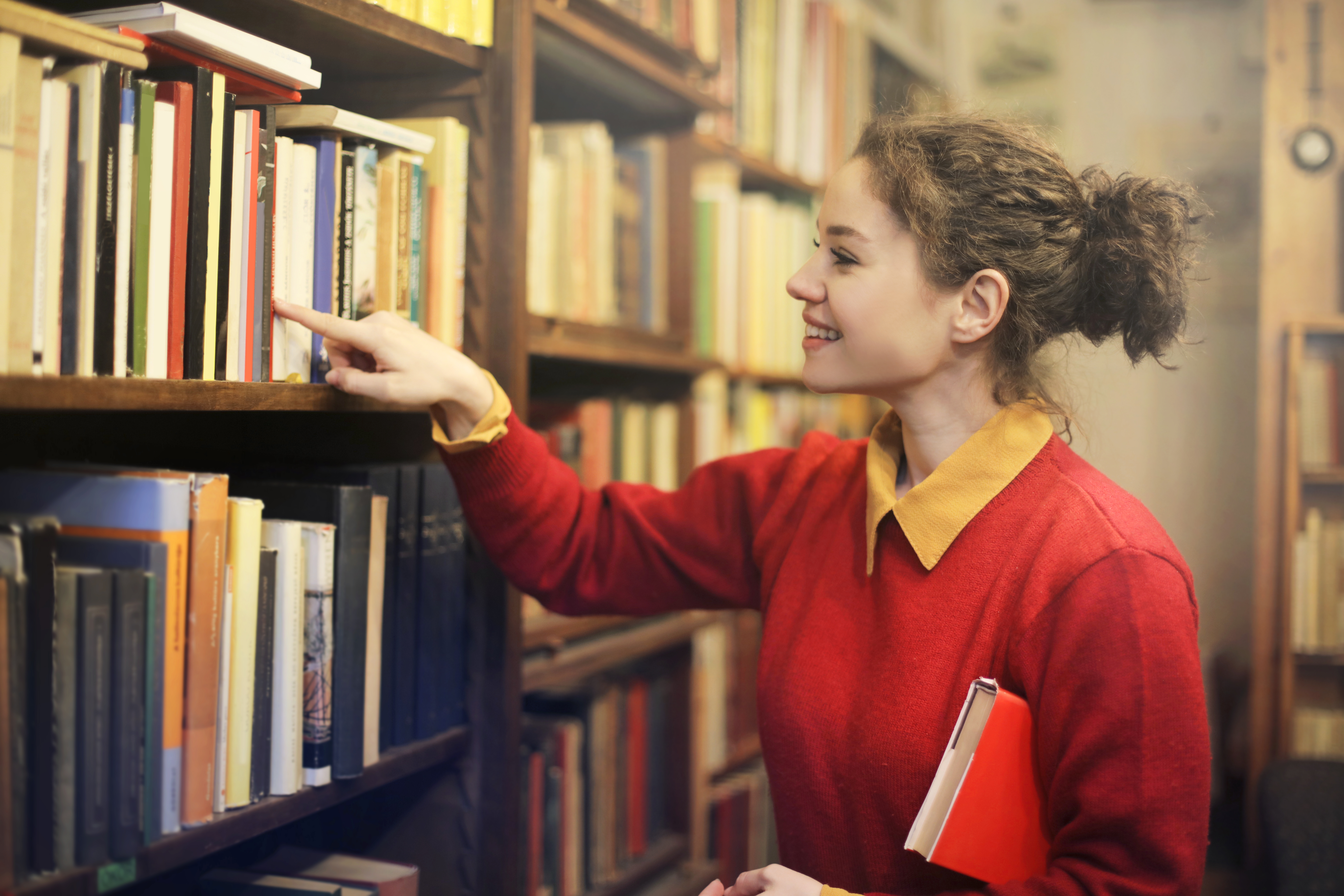 Een vrouw die een boek uit een boekenkast uitkiest