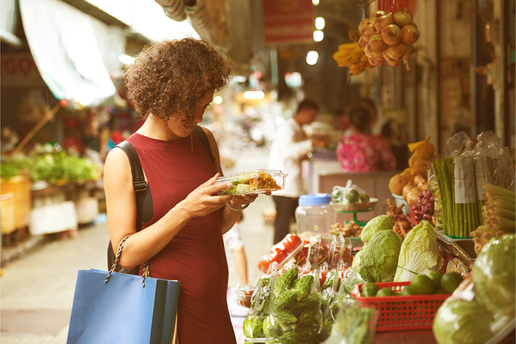 Vrouw met een winkeltas bekijkt producten op een markt
