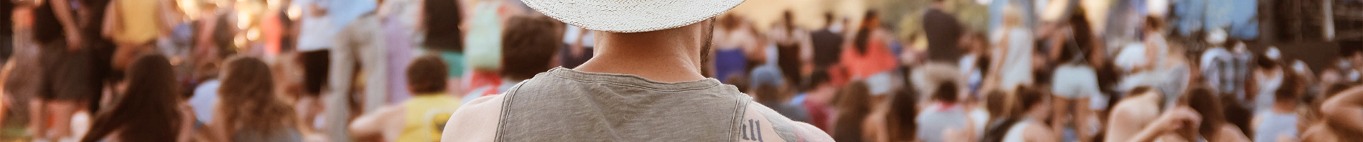 Een man zit op het gras en kijkt naar het podium op een festival