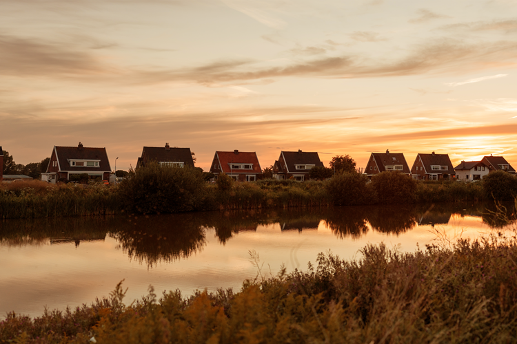Een rij huizen aan het water bij zonsondergang