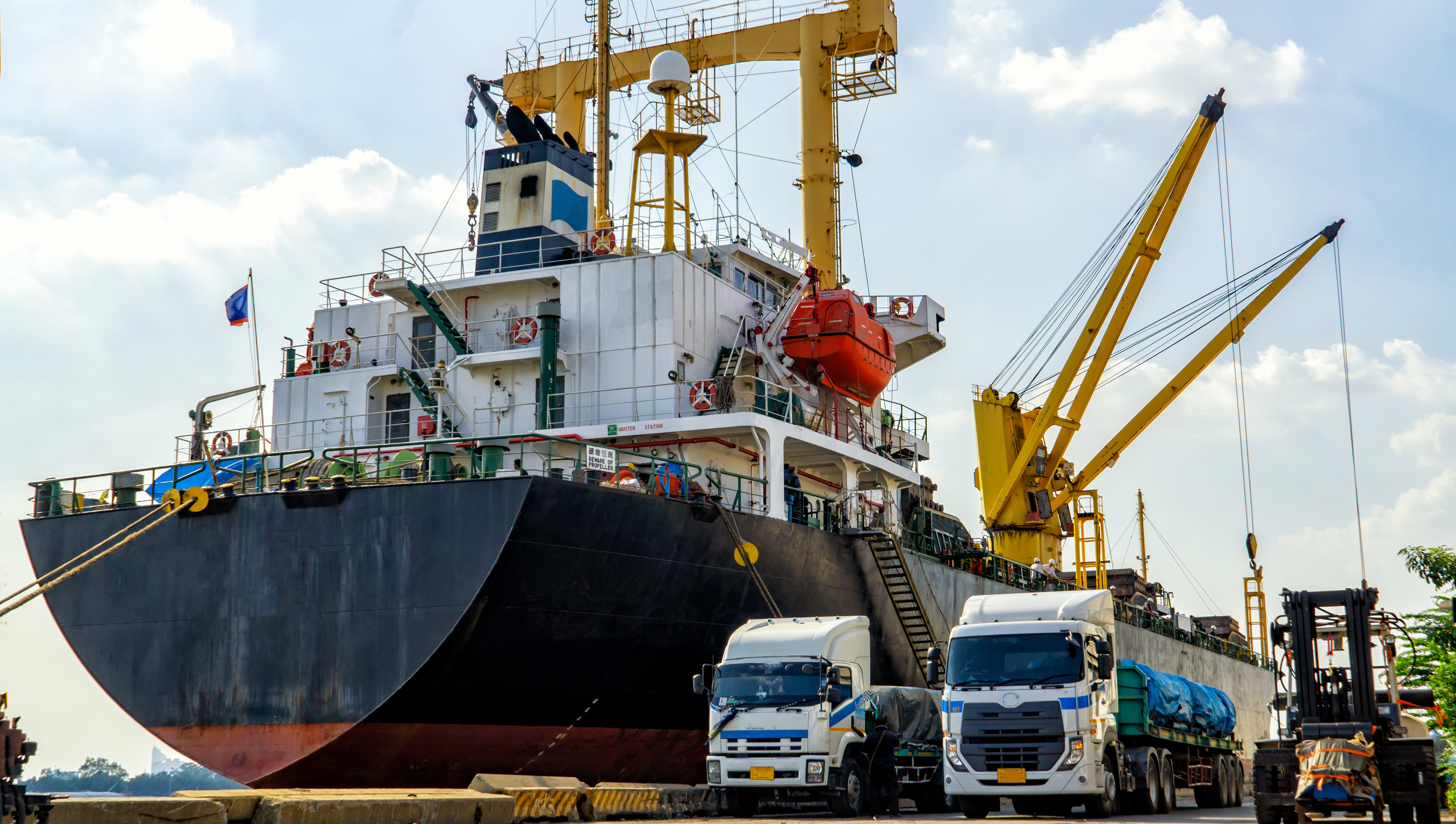 Een transportschip in de haven met vrachtwagens ervoor