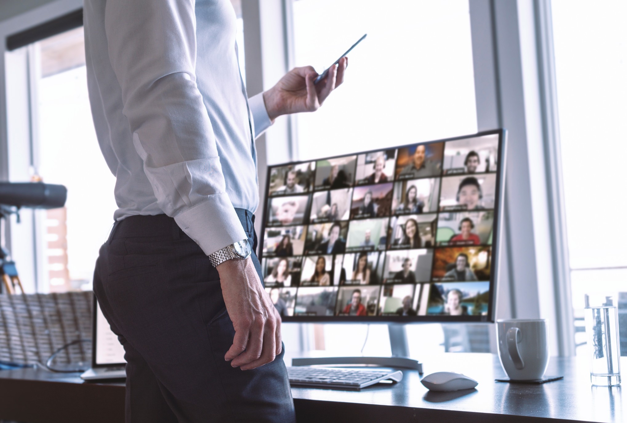 Man Using Video Chat On Smart Phone With Multiple Chat Screen On Desktop Computer While Working From T20 Rlaj6l