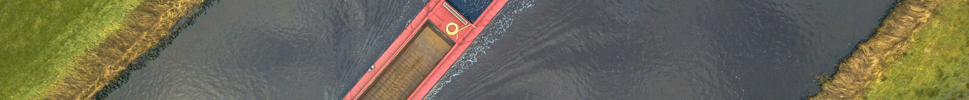 Een vrachtschip die vaart over de rivier