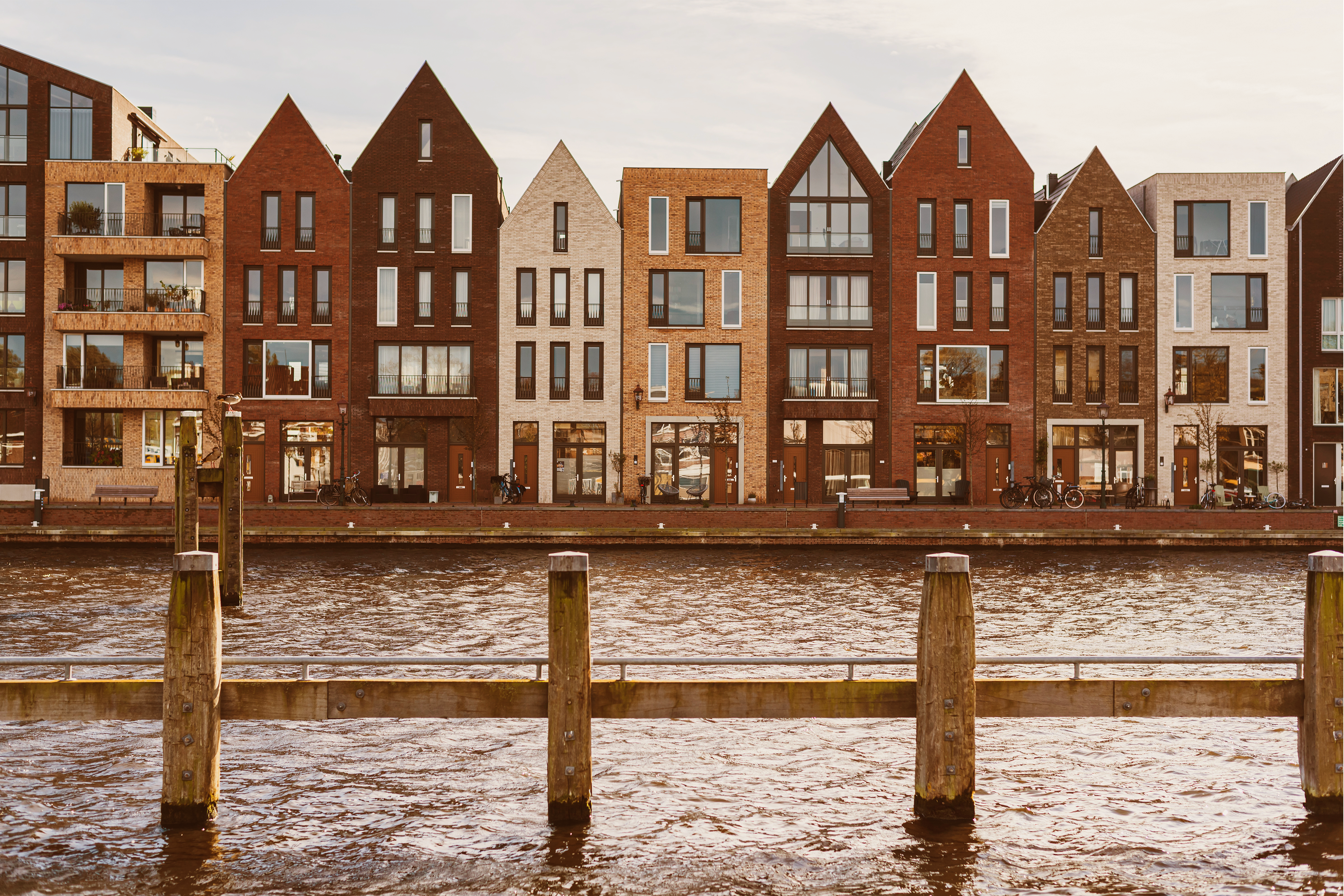 Een rij huizen aan het water met meerpalen op de voorgrond