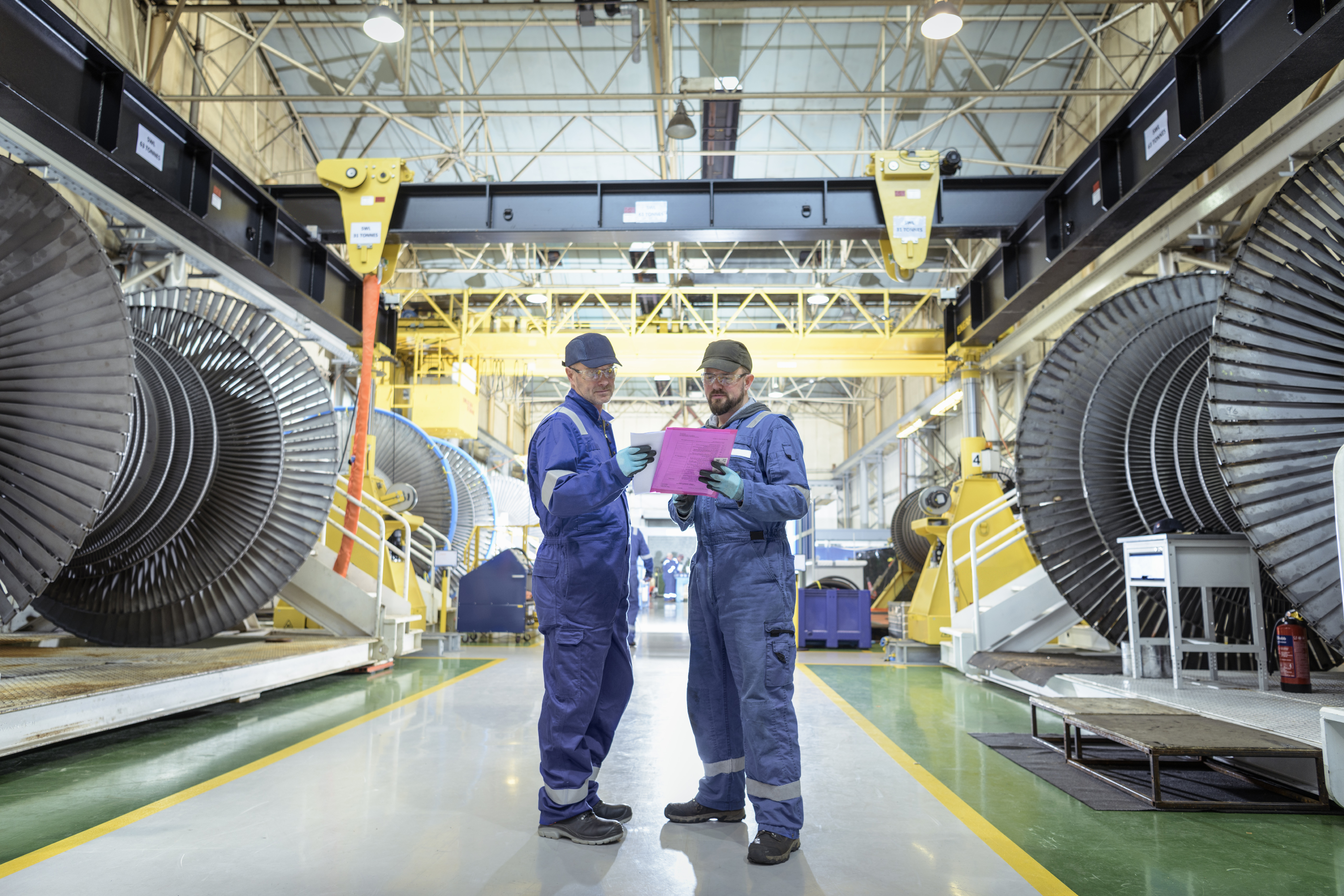 Twee technici overleggen in een hal met turbines