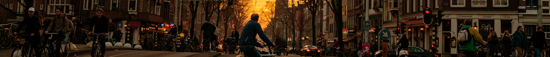 een fietser steekt een trambaan over in een stad met zonsondergang