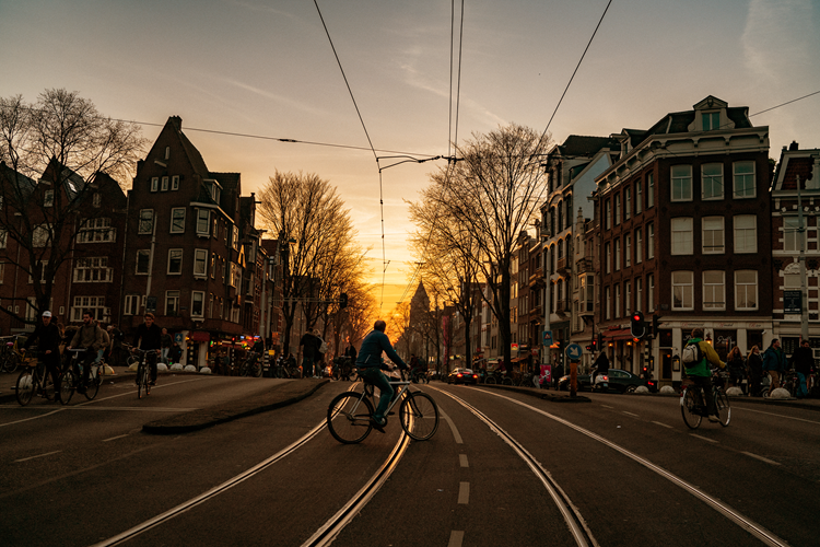 een fietser steekt een trambaan over in een stad met zonsondergang