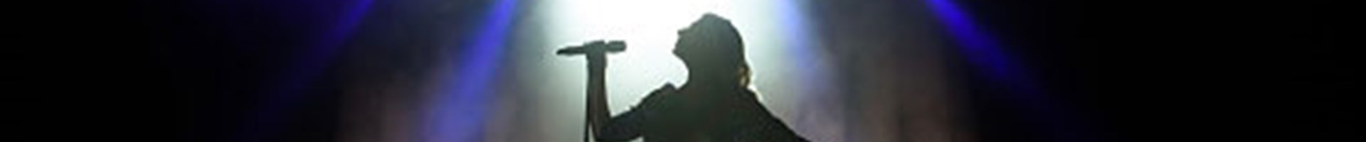 Een vrouw in de spotlight die zingt op een podium