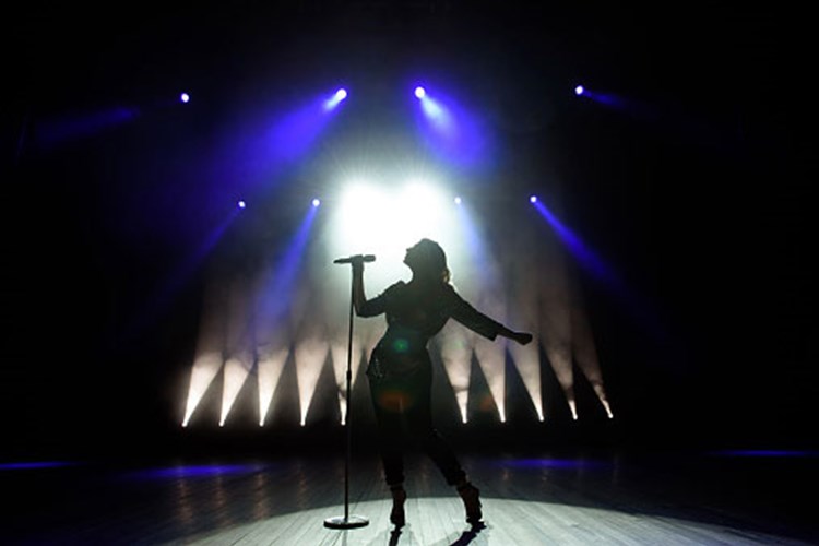 Een vrouw in de spotlight die zingt op een podium